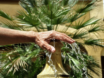 Close-up of cropped hand on fountain spraying water