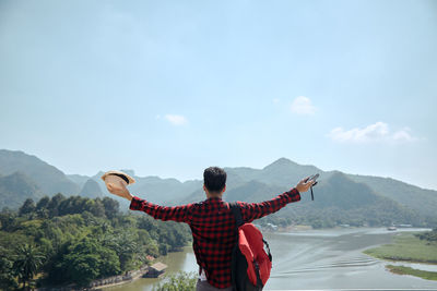 Rear view of man with arms outstretched against mountain range