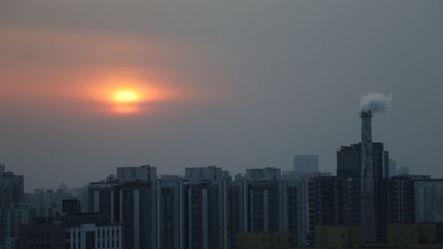 Modern cityscape against sky during sunset