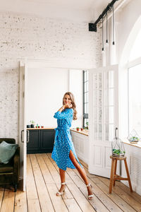 Portrait of young woman standing on floor at home