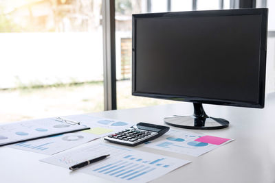 Close-up of paper and desktop pc on table