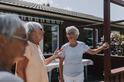 Smiling senior women talking inn garden during sunny day