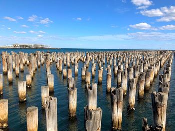 Panoramic shot of wooden posts on sea against sky