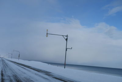 Street light on snow covered road against sky