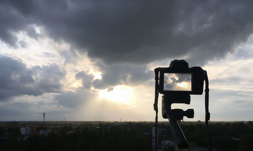 Camera photographing against sky during sunset