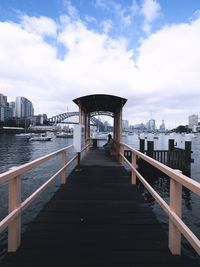 Pier over sea against sky in city