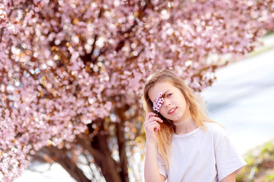 Portrait of young woman standing against trees