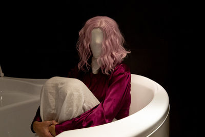 Woman with obscured face sitting in bathtub