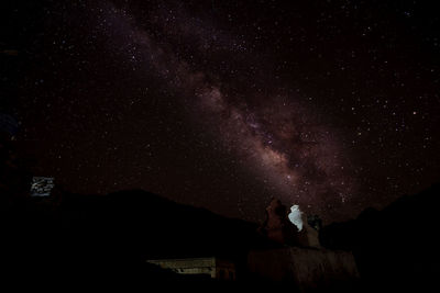 Low angle view of man standing against star field at night