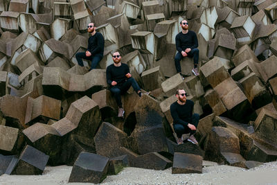 Multiple image of man sitting on rocks at beach