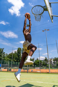 Young african american basketball player athlete in action jumping on artificial turf playing field