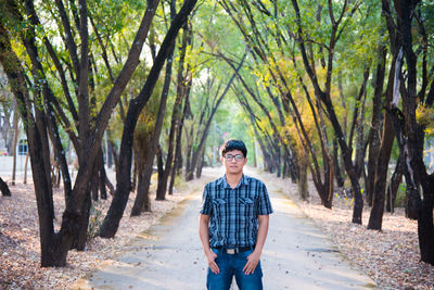 Portrait of young man standing on footpath at park