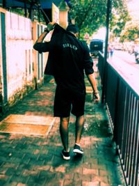 Rear view of man walking on footpath