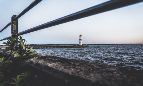 Lighthouse by sea against sky