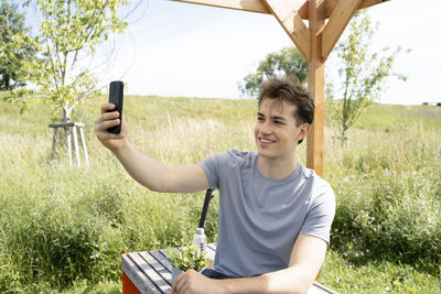 Young woman using mobile phone while sitting on field