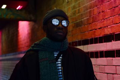 Portrait of man standing against illuminated wall