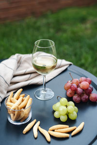 A glass of white wine with appetizers on the table.