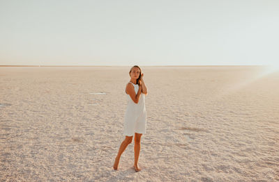 Full length of woman standing at beach against clear sky