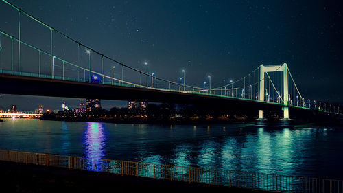 Illuminated bridge over river at night