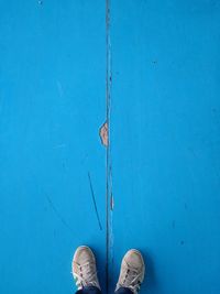 Low section of person standing on blue wall