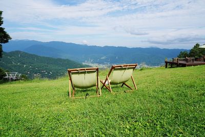 Chairs on field against sky