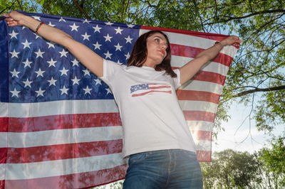 Young woman holding usa flag outdoors at sunset. patriotic holiday. independence day.