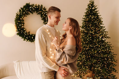 A couple in love hugging and relaxing on a christmas holiday in the decorated interior of the house