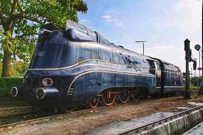 Train by railroad tracks against sky