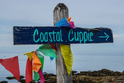 Low angle view of sign standing on beach against sky