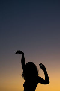 Silhouette woman in bird against sky during sunset