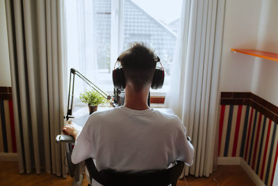 Teenage boy podcasting with microphone at home