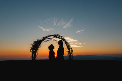 Silhouette couple standing against sky during sunset