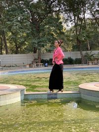 Woman standing by swimming pool against trees