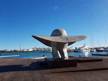 Pier at harbor against clear blue sky