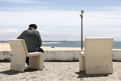 Rear view of a man overlooking calm sea