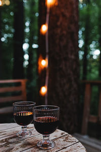 Two glasses of red wine standing on the wooden table on the outdoor patio. summer cabin getaway