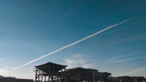 Low angle view of vapor trails in building against sky