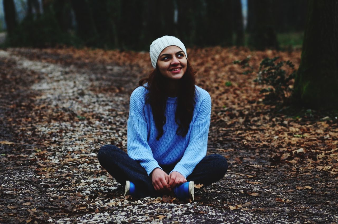 one person, land, real people, lifestyles, leisure activity, forest, tree, front view, sitting, young adult, day, nature, young women, autumn, clothing, full length, casual clothing, portrait, focus on foreground, outdoors, change, warm clothing, beautiful woman