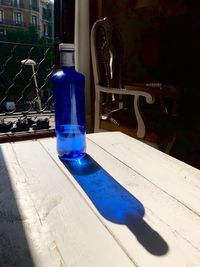 Close-up of blue glass with bottle on table