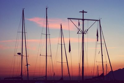 Silhouette masts against sky during sunset