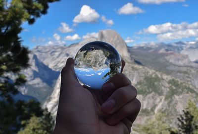 Close-up of hand holding crystal ball with mountain reflection