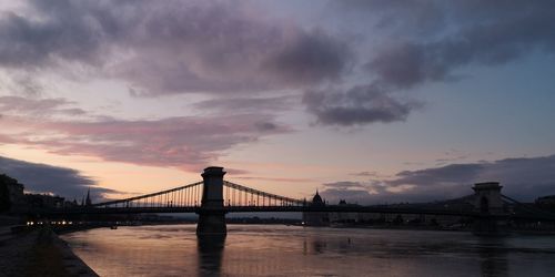 Bridge over river against cloudy sky