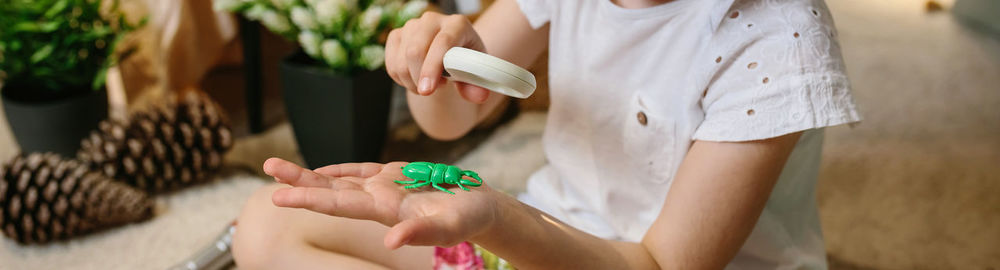 Unrecognizable girl playing observing toy bugs with a magnifying glass