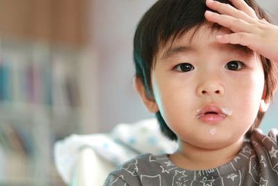 Close-up portrait of messy boy sitting at home