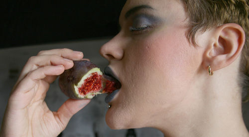 Close-up of young woman eating fig
