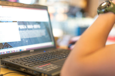 Cropped hand using laptop at table