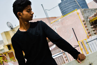 Young man looking down while standing on building terrace