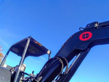 Low angle view of road sign against clear blue sky