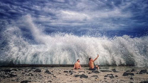 People relaxing on beach against sky