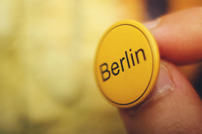 Close-up of hand holding yellow badge with text